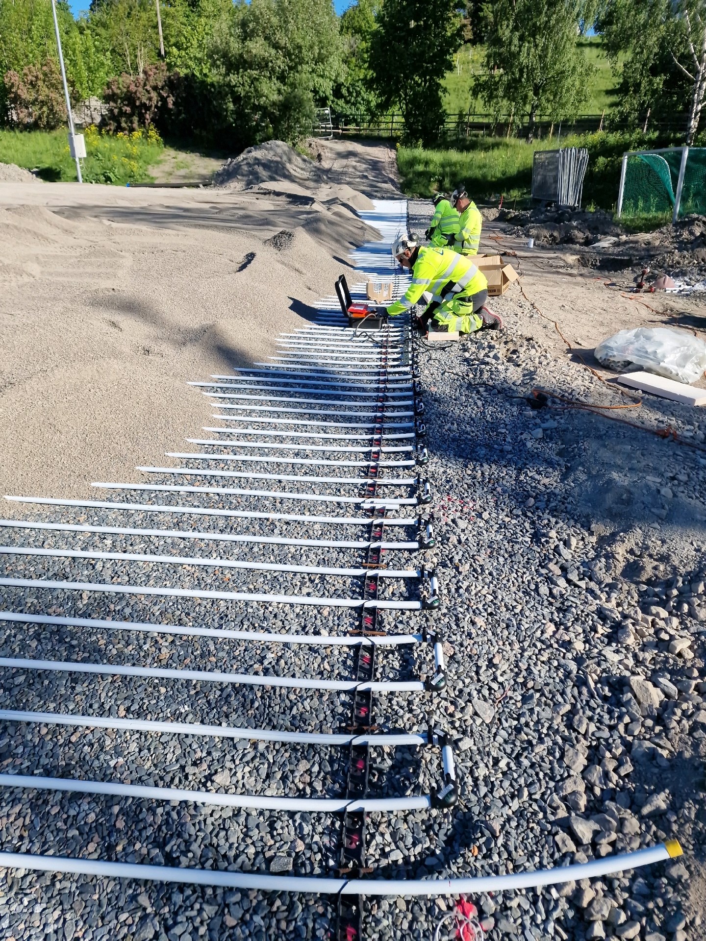 Banerør for vannbåren undervarme rulles ut og legges i grid over hele banen