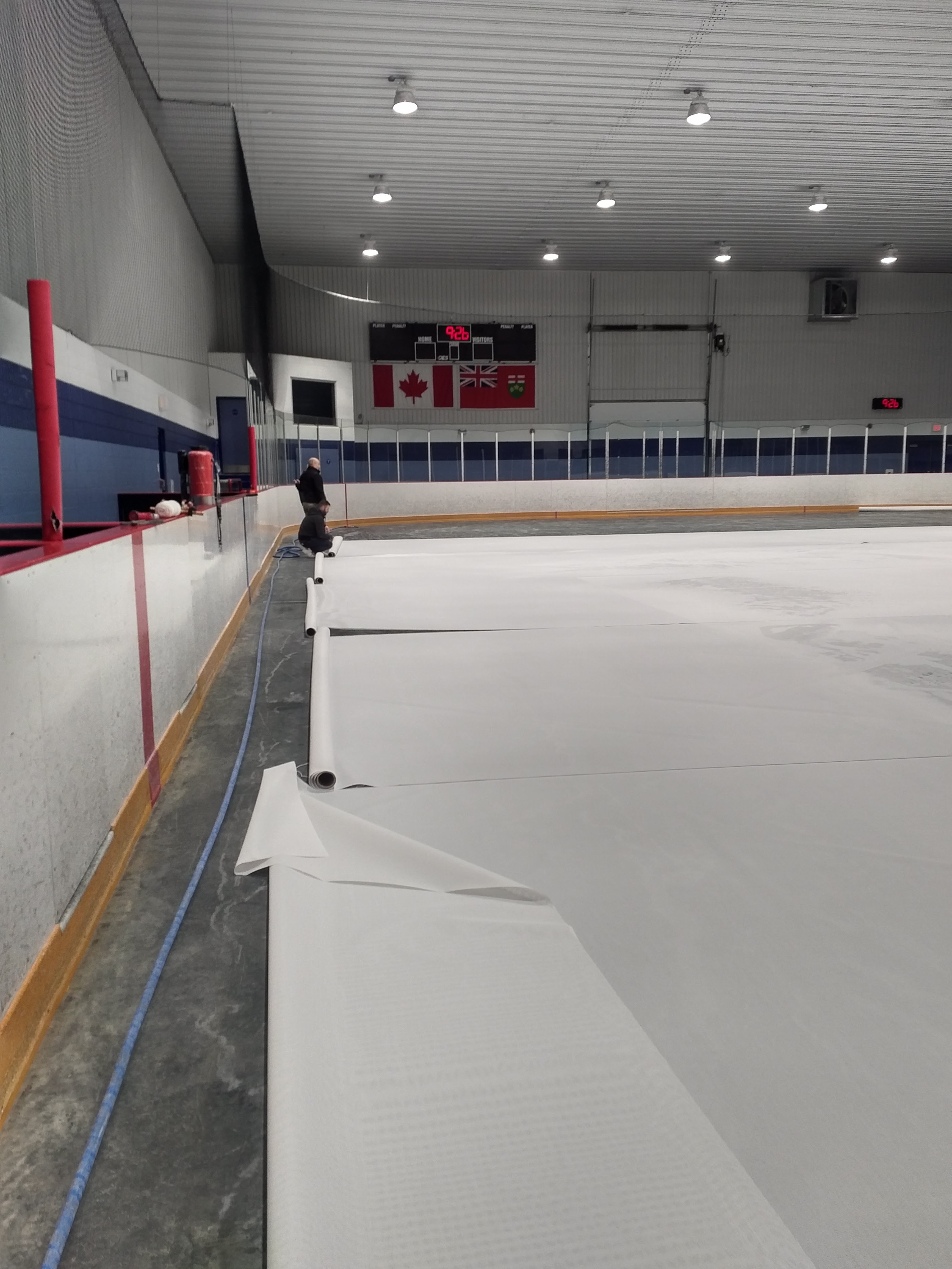 Hvite vinylpaneler fra Arena Panel Kit rulles ut langs vantet i ishall